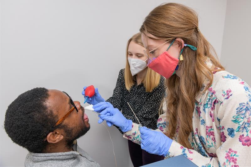 Students place sensors on the tongue of a research participant
